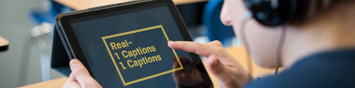 A student using a tablet with the text 'Real Captions' displayed on the screen.